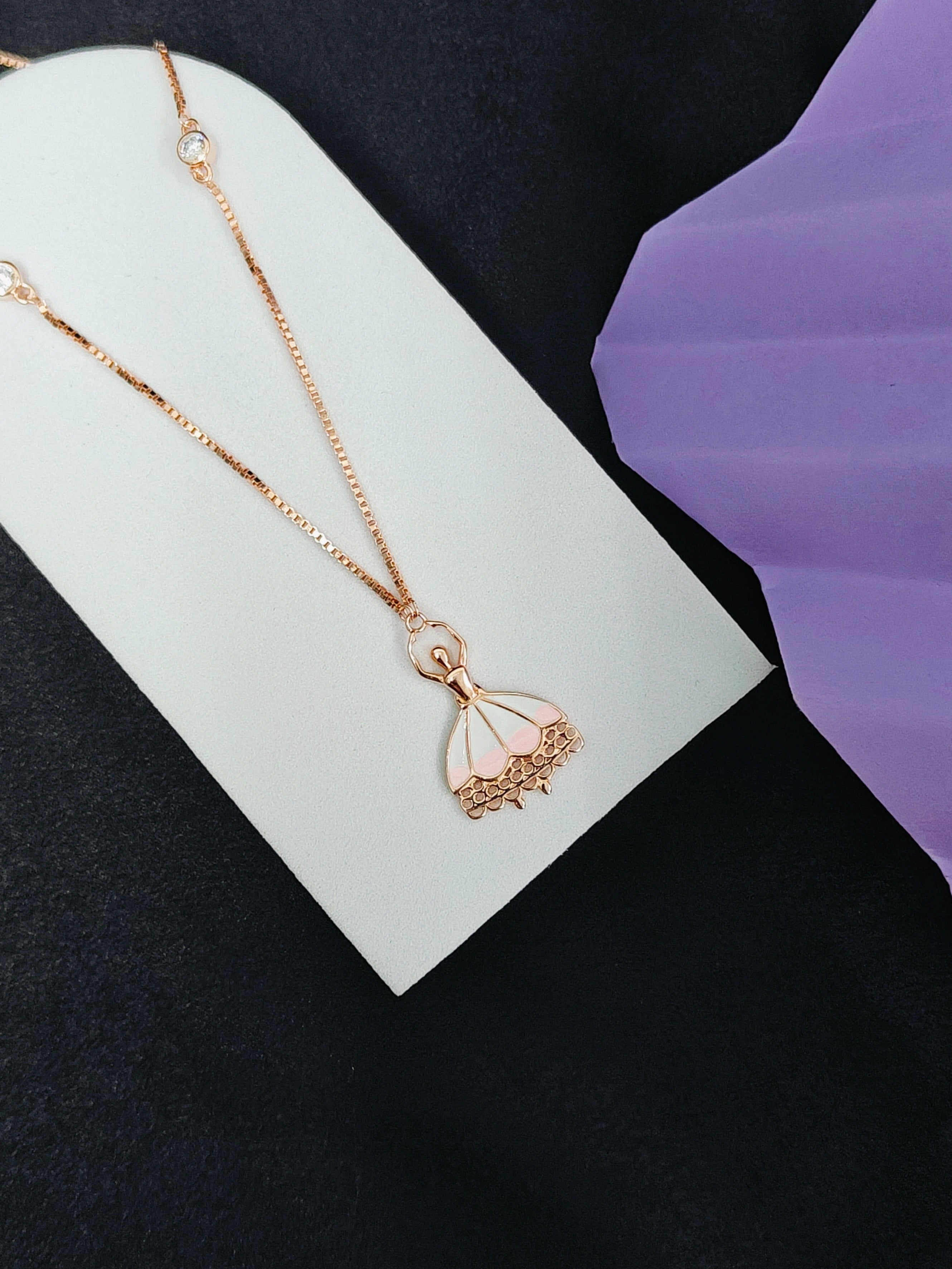 Rose gold necklace with a delicate pendant on a white card against a black background